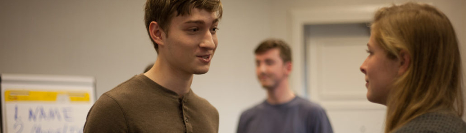 DISCOVER PAGE Two men standing in a room with one man looking at the camera.